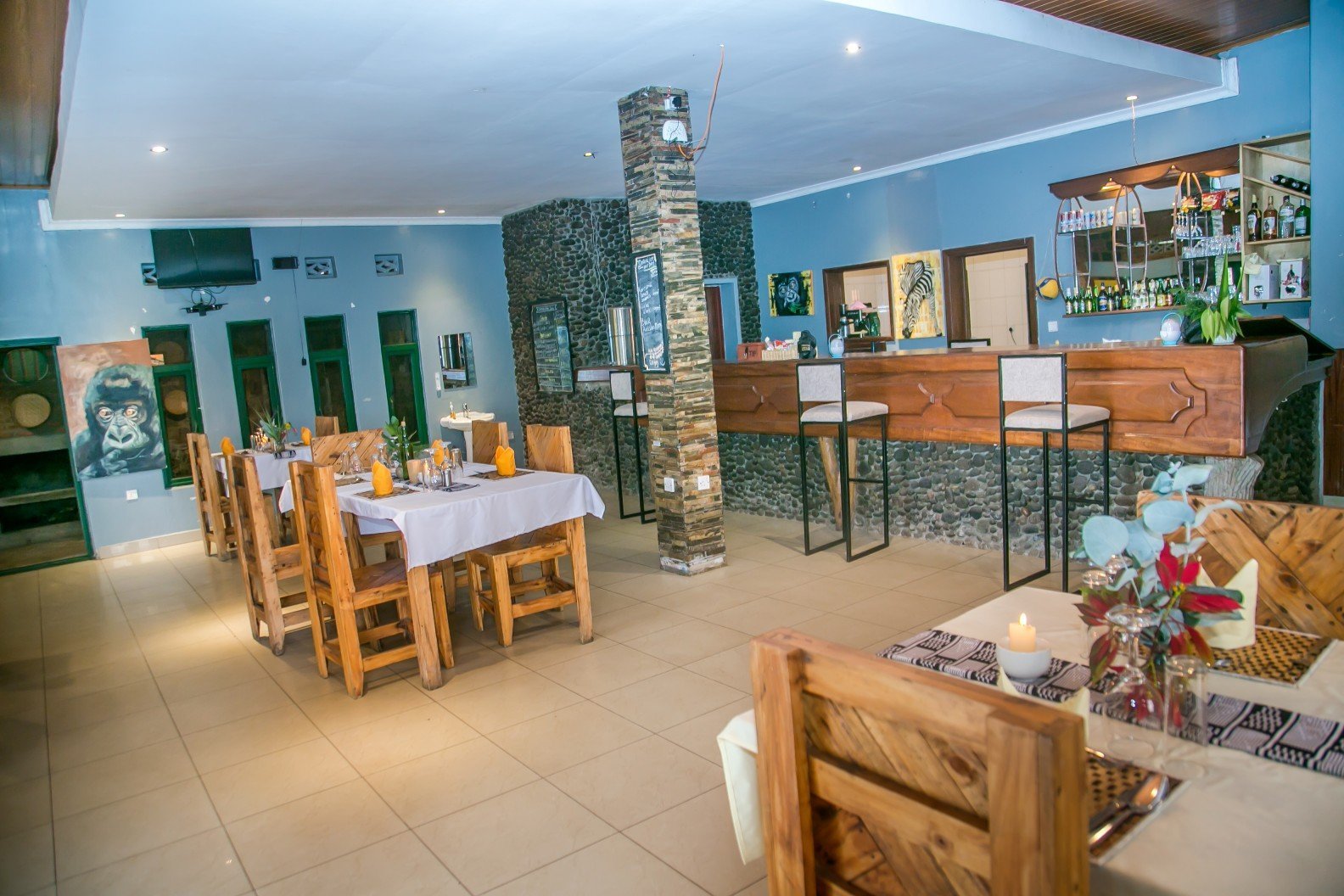 Restaurant dining room with wooden tables, white linen and a stone-clad bar