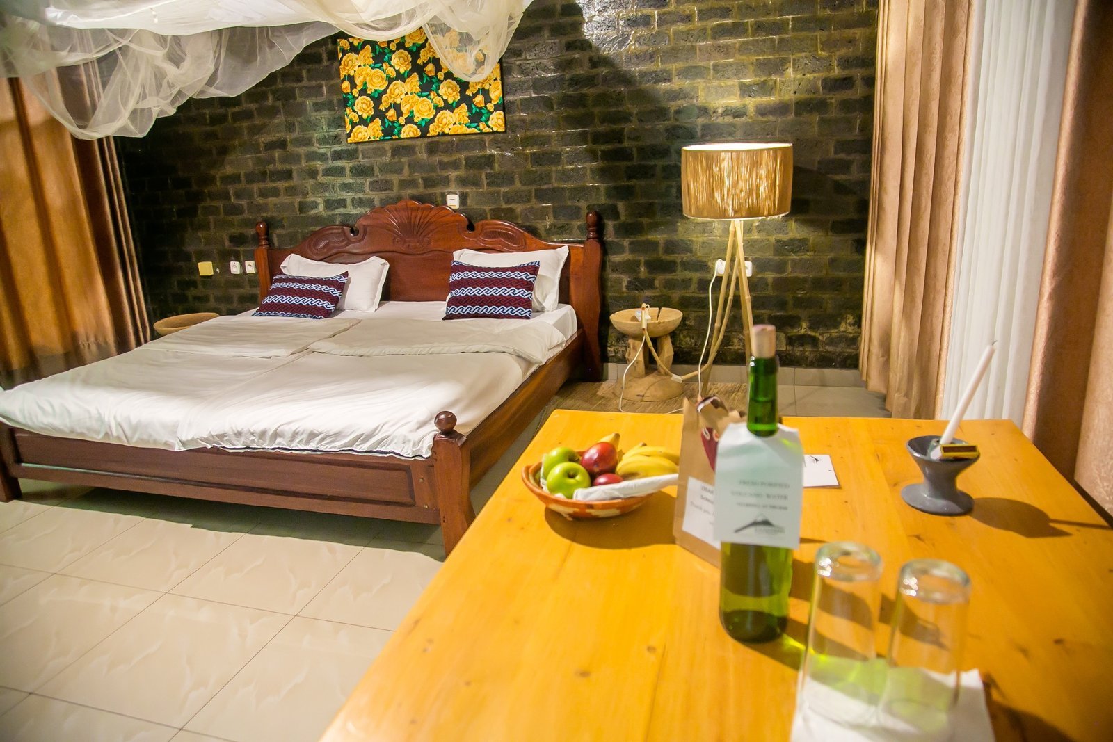 Double room with a wooden bed, brick feature wall and warm lamp light